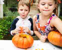 Free photo young kids carving halloween jack-o-lanterns