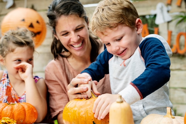 Young kids carving Halloween jack-o-lanterns