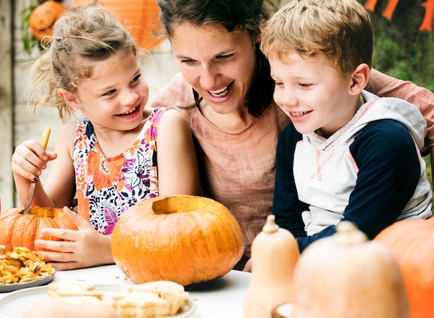 Young kids carving Halloween jack-o-lanterns