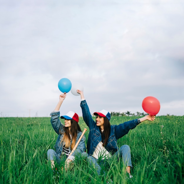 Free photo young ladies having fun in summer field with different colors balls