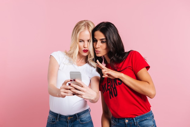 Young ladies making selfie and grimacing isolated