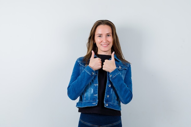 Free photo young lady in blouse, jacket showing double thumbs up and looking confident , front view.