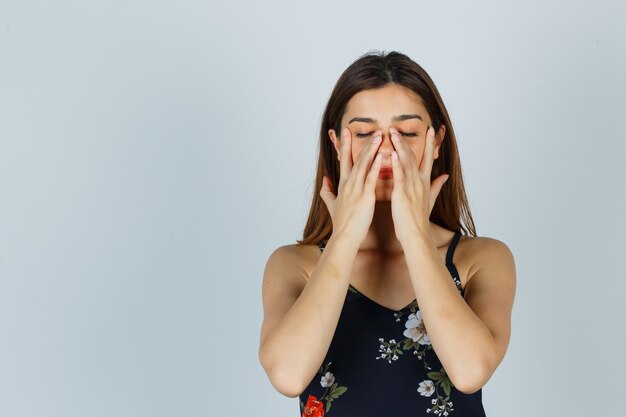 Young lady in blouse pretending to rub face mask on around nose zone and looking relaxed , front view.