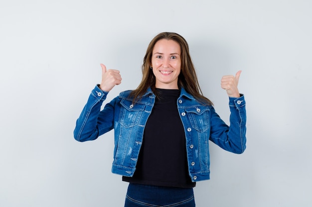 Young lady in blouse showing double thumbs up and looking confident , front view.