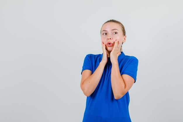 Free Photo young lady in blue t-shirt looking away with hands on cheek