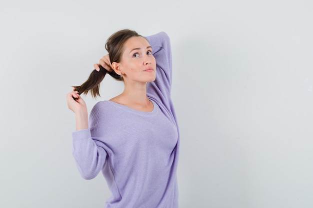 Free photo young lady in casual shirt holding her strand and looking pensive