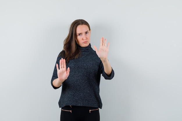 Young lady in casual shirt showing refusal gesture and looking serious 