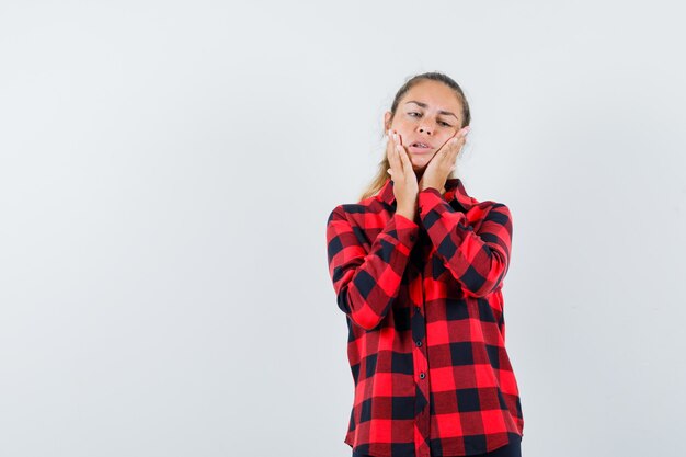 Young lady in checked shirt suffering from toothache and looking uncomfortable