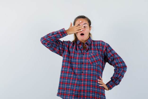 Free Photo young lady in checked shirt yawning and looking sleepy , front view.