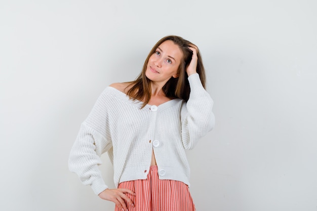 Young lady comb hair with hand in cardigan and skirt looking attractive isolated