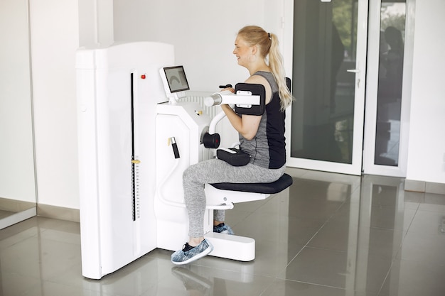 Free photo young lady doing exercises on simulator in phisiotherapy room