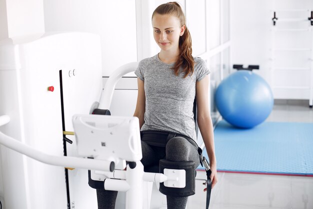 Young lady doing exercises on simulator in phisiotherapy room