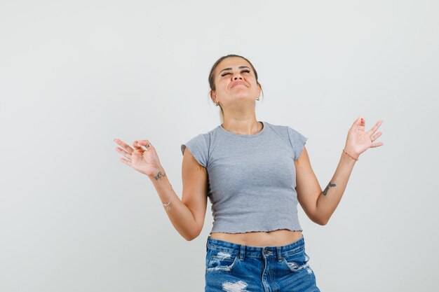 Young lady doing meditation with closed eyes in t-shirt, shorts and looking peaceful