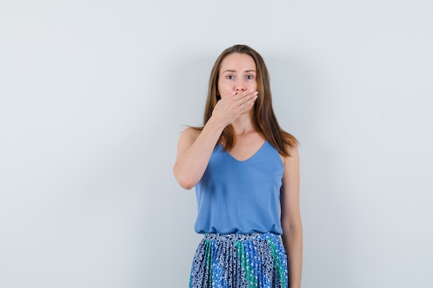 Free Photo young lady holding hand on mouth in singlet, skirt and looking surprised