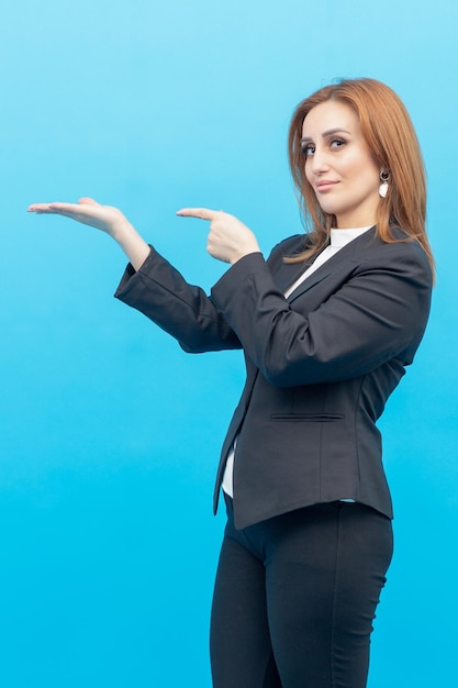 Young lady holding her hand open in air and standing on blue background