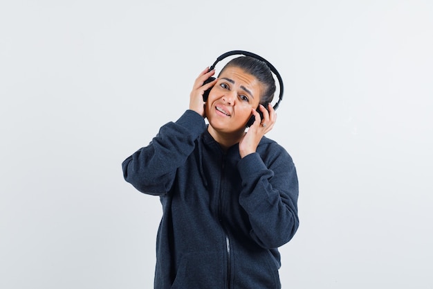 Free Photo young lady in jacket holding hands on earphones 