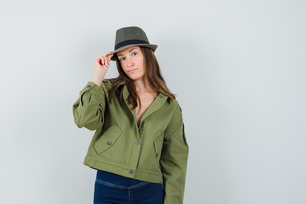 Free photo young lady in jacket pants holding her hat and looking elegant