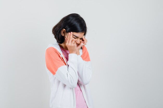 Young lady in jacket, pink shirt massaging her temples and looking stressful