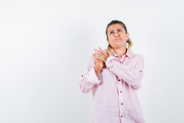 Young lady keeping hands on chest in pink shirt and looking hesitant