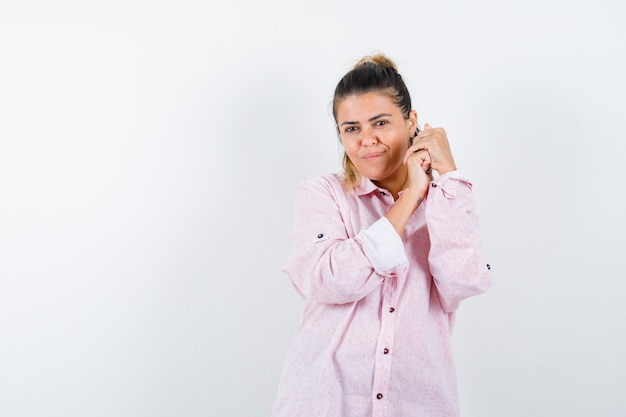 Young lady keeping hands clasped in pink shirt and looking charming