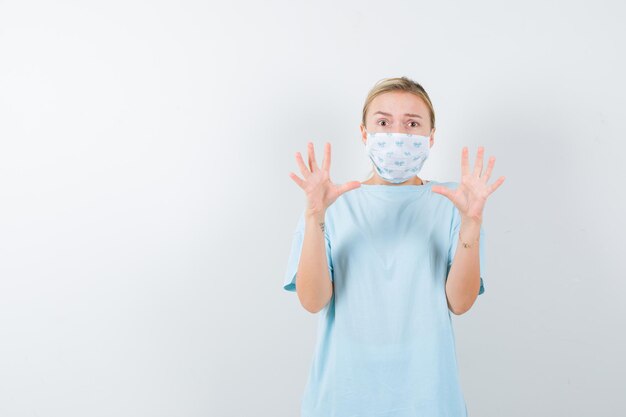 Young lady keeping hands in surrender gesture in t-shirt isolated