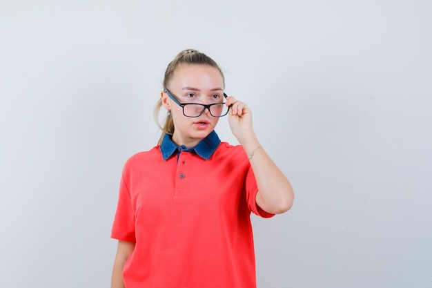 Young lady looking away over glasses in t-shirt and looking puzzled