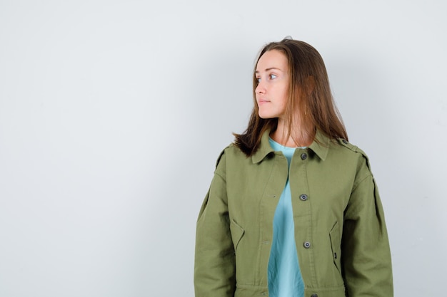 Young lady looking away in t-shirt, jacket and looking pensive , front view.