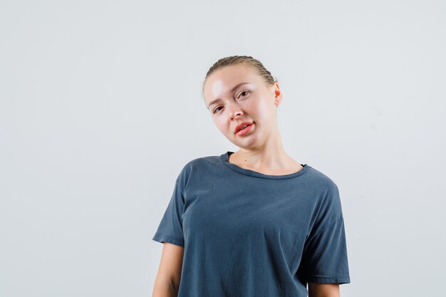 Young lady looking at camera and smiling in grey t-shirt front view.