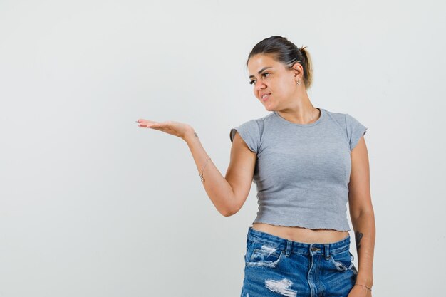 Young lady looking at her palm spread in t-shirt, shorts