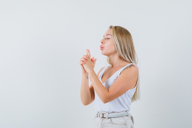 Young lady making pistol gesture in white blouse and looking prepared