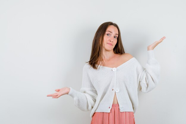 Young lady making scales gesture in cardigan and skirt looking pretty isolated