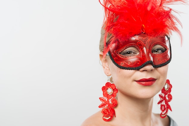 Free Photo young lady in mask with red feathers and earrings 