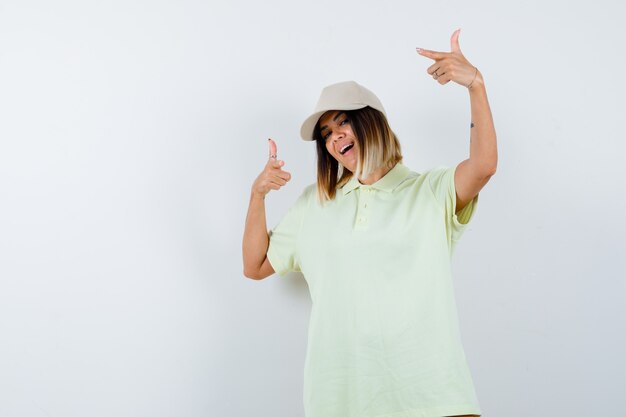 Free Photo young lady pointing aside in t-shirt, cap and looking happy. front view.