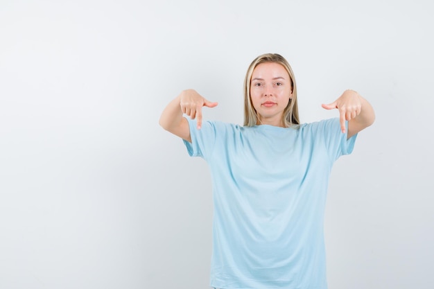 Free Photo young lady pointing down in t-shirt and looking confident isolated