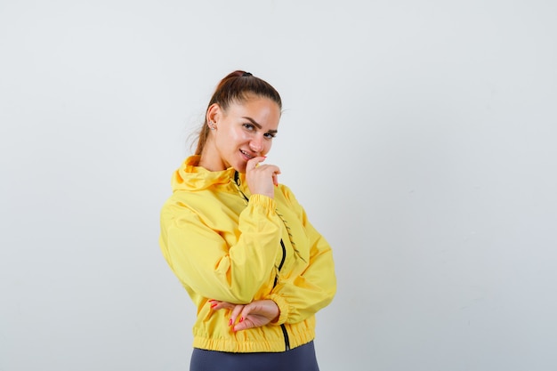 Young lady posing in yellow jacket and looking cheery. front view.