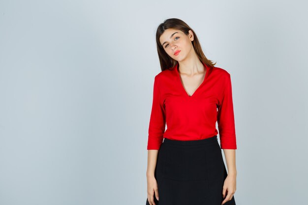 Young lady posingin red blouse, black skirt and looking pretty