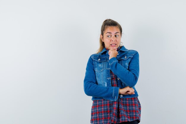 Young lady propping chin on fist in shirt, jacket and looking worried , front view.