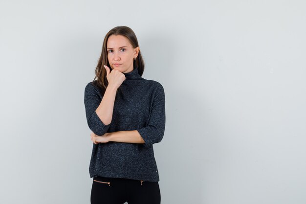 Young lady propping chin on hand in shirt