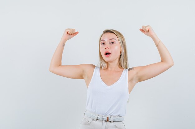 Young lady raising her arms for showing her power in white blouse and looking flexible