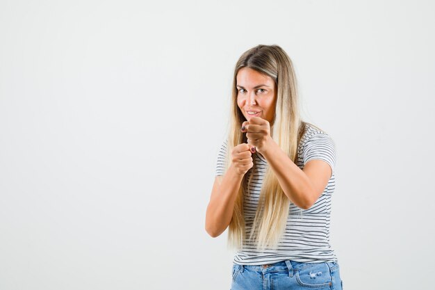 Young lady raising her fists in t-shirt and looking crazy. front view.