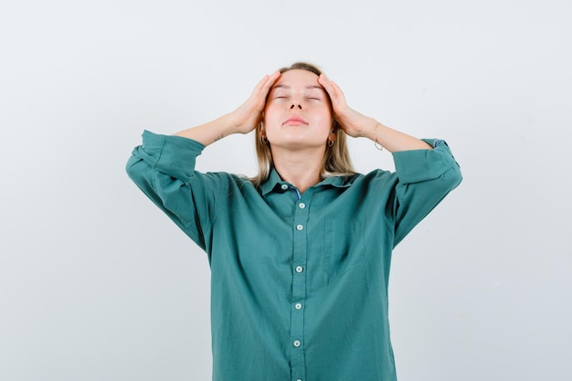 Free photo young lady rubbing her temples in green shirt and looking relaxed