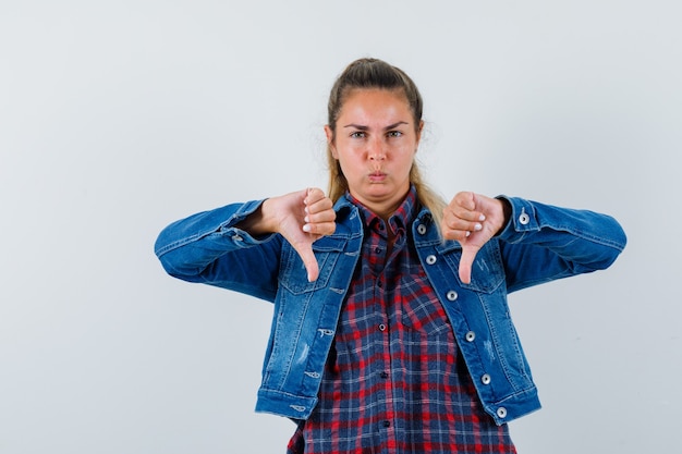 Free photo young lady in shirt, jacket showing double thumbs down and looking gloomy , front view.