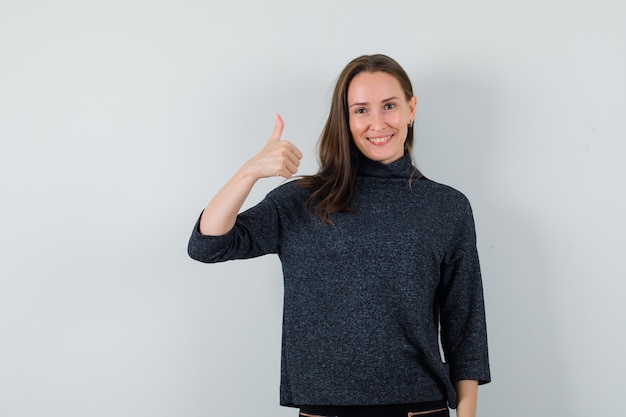 Young lady in shirt showing thumb up and looking cheerful 