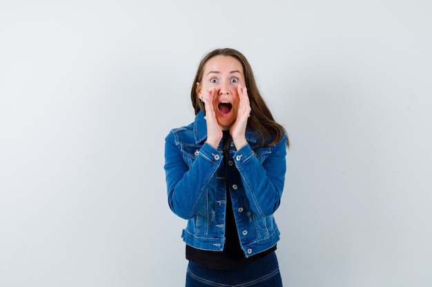 Young lady shouting or announcing something in blouse and looking happy, front view.