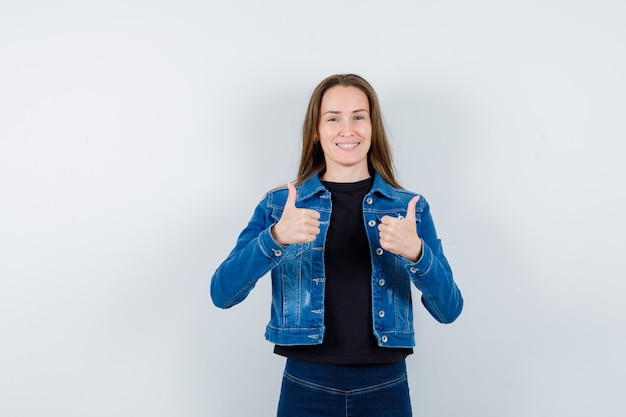 Free photo young lady showing double thumbs up in shirt, jacket and looking confident, front view.