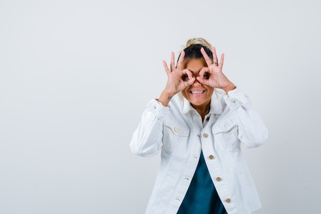 Free Photo young lady showing glasses gesture in shirt, white jacket and looking amused , front view.