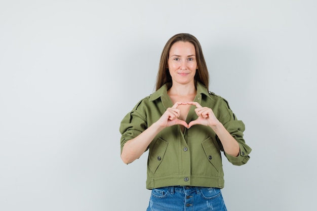 Free photo young lady showing heart gesture in green jacket shorts and looking cute