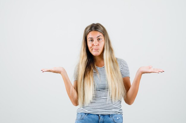 Young lady showing helpless gesture in t-shirt and looking displeased. front view.