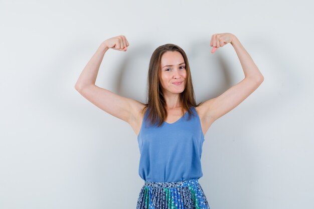 Young lady showing muscles of arms in singlet, skirt and looking confident