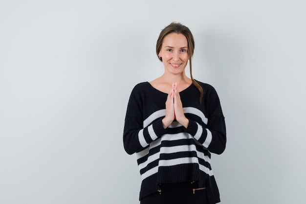 Free Photo young lady showing namaste gesture in shirt and looking cheerful